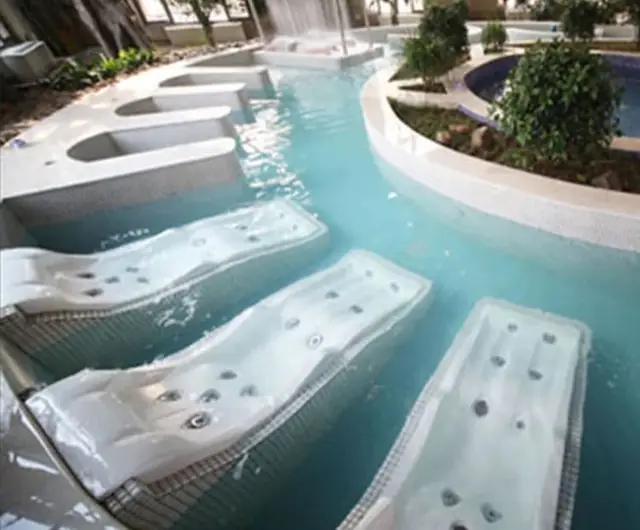 Leisure-pool relaxation zone with massage beds and a curved channel