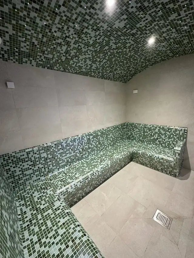 Steam room in green mosaic with built-in benches